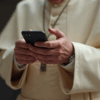 Manos del Papa usando un celular mientras busca información en internet